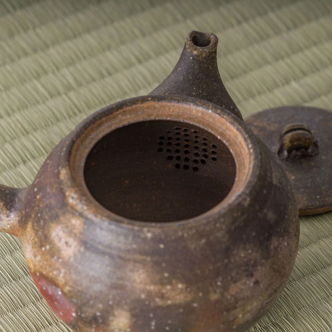 Close-up into the kyusu interior showing the pierced ceramic strainer holes at the spout