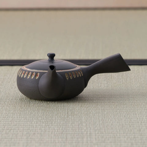 Low wide dark kyusu teapot with a carved oval band and side handle, viewed slightly from above.