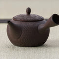 Dark purple-brown clay kyusu with a carved basket-weave texture and lid, side view.