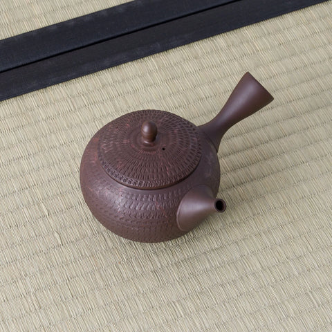 Reddish-brown clay kyusu with a combed lid and side handle, viewed from above at an angle.
