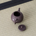 Purple-brown kyusu with a side handle, lid removed to show the mesh strainer, floral inlay, on a tatami mat.