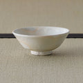 Cream-white glazed shallow bowl with a pink blush, side view on a tatami mat.