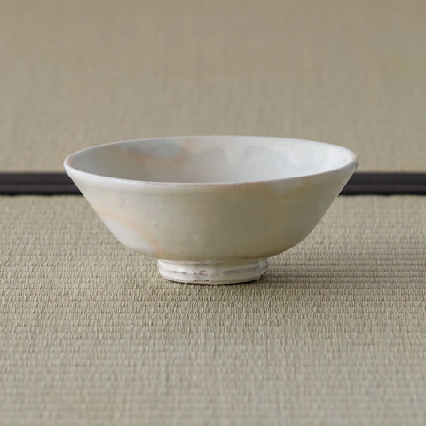 Cream-white glazed shallow bowl with a pink blush, side view on a tatami mat.