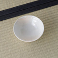 Cream-white glazed shallow bowl viewed from above, glazed interior, on a tatami mat.