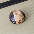 Underside of a black Kuro-Oribe chawan showing its unglazed foot and painted clay panel wrapping the side.