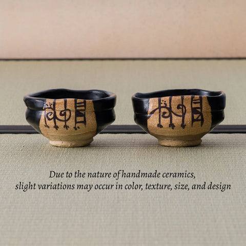 Two shoe-shaped black chawan with painted motifs, alongside a note that handmade pieces vary slightly.