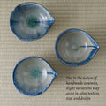 Three handmade ceramic tea bowls with blue and green glaze variations, arranged on a beige tatami mat background with a text overlay explaining variations in handmade ceramics.