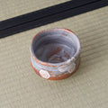 Overhead view of a grey-blue Shino chawan with rust-toned rim and small hexagon motifs.