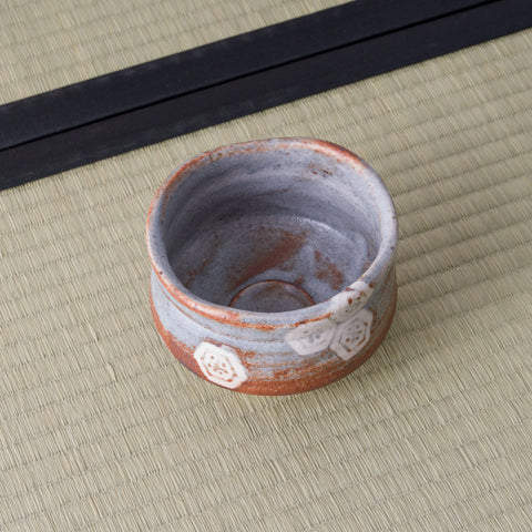 Overhead view of a grey-blue Shino chawan with rust-toned rim and small hexagon motifs.