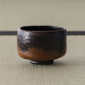 Kuro-raku black raku matcha bowl, front view showing the irregular hand-formed rim
