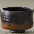 Kuro-raku black raku matcha bowl, front close-up of the matte black glaze and rust patches