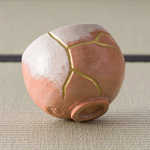 Aka-raku Seppo red raku matcha bowl, angled view of the white glaze and gold-outlined patches