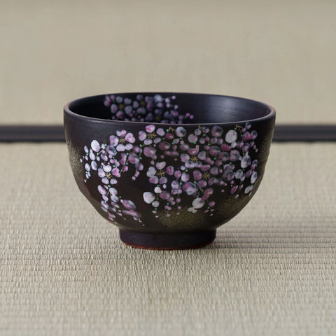 Black Weeping Sakura Chawan on tatami, its side painted with trailing sprays of pink and white cherry blossom