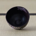 Black Weeping Sakura Chawan tipped forward to reveal the dark interior, blossoms scattered just below the rim