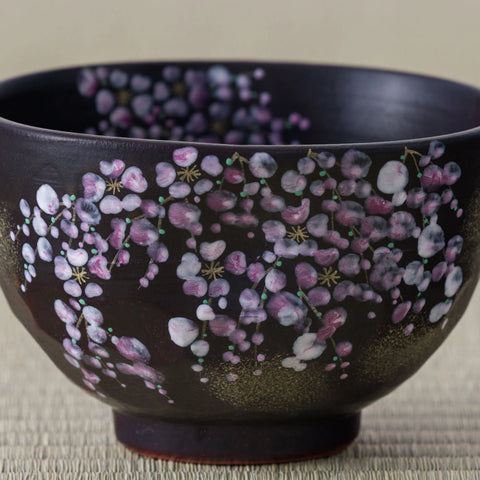 Detail of the hand-painted weeping cherry on the Black Weeping Sakura Chawan, pink and white petals with gold speckling