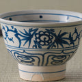Close view of a blue-and-white porcelain bowl with a peony-and-bamboo scroll design.