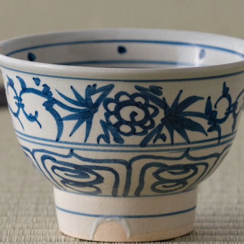 Close view of a blue-and-white porcelain bowl with a peony-and-bamboo scroll design.