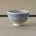 Pale blue striped tea bowl, side view on a tatami mat.