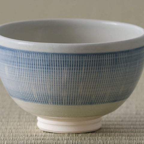 Pale blue and white striped tea bowl, side view on a tatami mat.