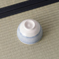 White bowl with a pale blue fine-striped exterior, inverted to show its foot.