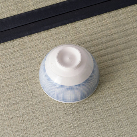 White bowl with a pale blue fine-striped exterior, inverted to show its foot.
