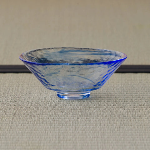Shallow pale blue glass tea bowl with a blue rim, side profile on a tatami mat.