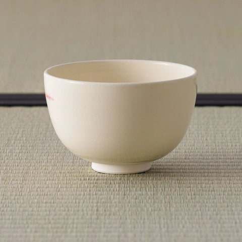 Cream tea bowl shown from its plain side, side view on a tatami mat.