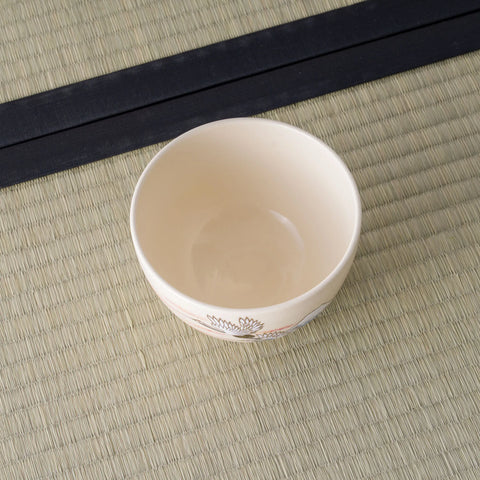 Cream tea bowl viewed from above, glazed interior, on a tatami mat.