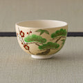 Cream tea bowl painted with pine, bamboo and red-and-white plum (shochikubai), side view.
