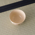 Cream-peach bowl viewed from above, interior with a painted sprig at the base.