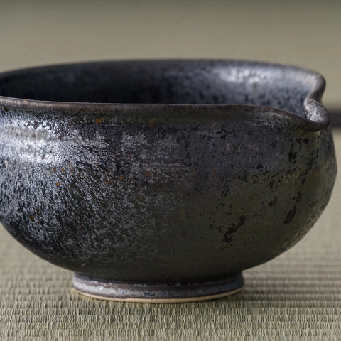 Close-up of the chawan's lustrous dark glaze and pouring lip