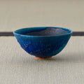 Deep blue glazed tea bowl, side view on a tatami mat.