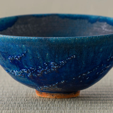Deep blue glazed tea bowl, close view of the interior, on a tatami mat.
