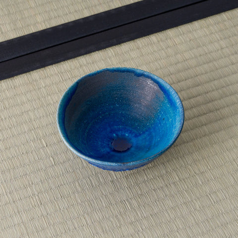 Deep blue glazed tea bowl viewed from above, showing the interior, on a tatami mat.