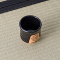 Overhead view of a black yunomi showing its dark glazed interior and painted side panel.