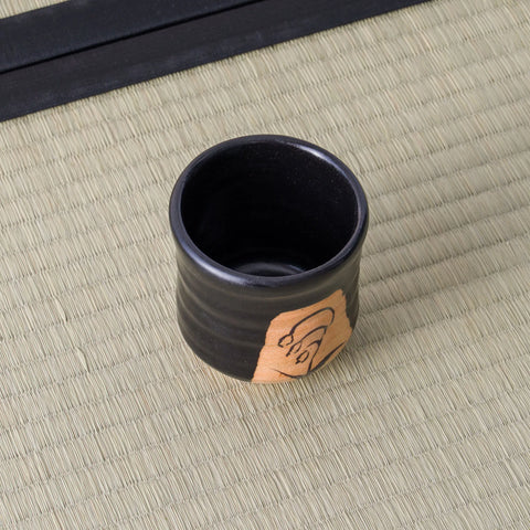 Overhead view of a black yunomi showing its dark glazed interior and painted side panel.
