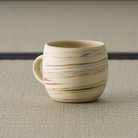 Striped beige mug seen from the front with the handle to the right