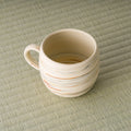 High angle looking into the beige striped mug showing the glazed interior