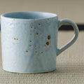 Close-up of the speckled glaze and handle of the blue-grey mug