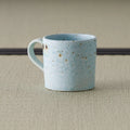 Side view of the speckled blue-grey mug showing the curved loop handle