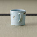 Speckled blue-grey mug seen from the front with the handle to the right