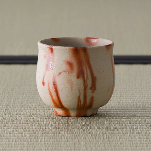 Front view of the cream yunomi with vivid orange-red hidasuki flame streaks