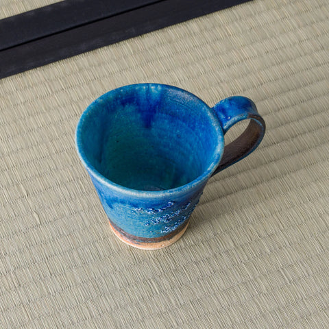 Blue glazed mug with a handle, viewed from above showing the interior, on a tatami mat.