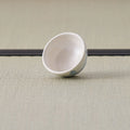 Small white cup with a blue design, tipped on its side showing the interior.