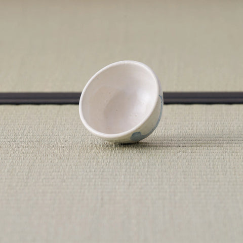 Small white cup with a blue design, tipped on its side showing the interior.