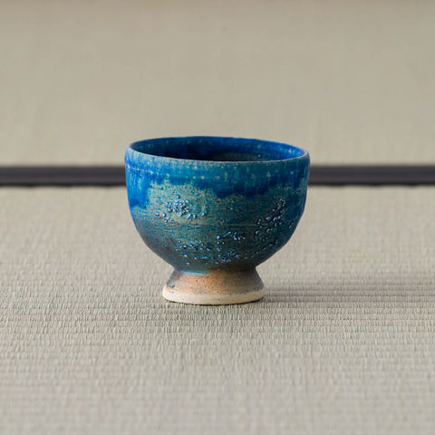 Deep blue glazed footed cup, side view on a tatami mat.