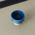 Deep blue glazed cup viewed from above, showing the interior, on a tatami mat.