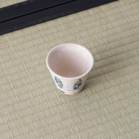 Small white cup with a blue floral design, on a tatami mat.