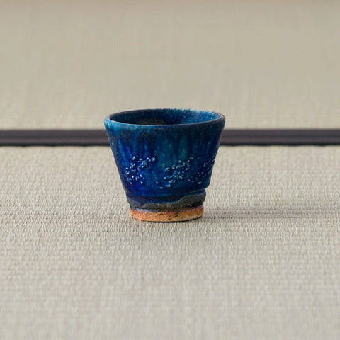 Deep blue speckled cup, side view on a tatami mat.