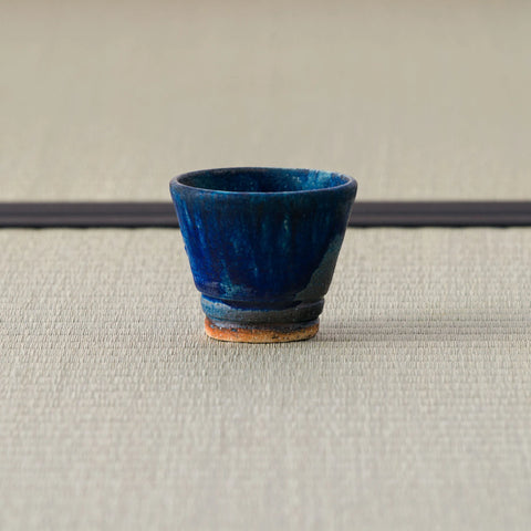 Deep blue speckled cup, side view on a tatami mat.